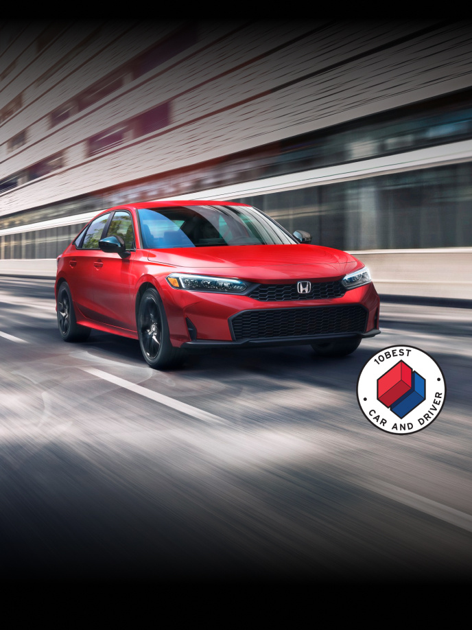 2026 Honda Civic Sedan Civic Sedan Sport in Rallye Red front view driving on a street with overlapping Car and Driver 10Best logo (Compact Sedan).
