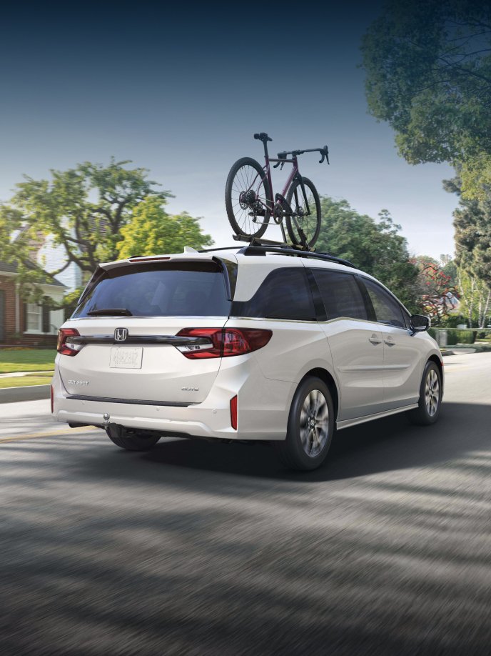 2026 Honda Odyssey Elite in Platinum White Pearl driving through residential neighborhood.