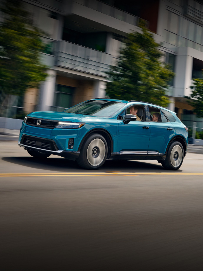 2026 Honda Prologue Elite in North Shore Pearl, driving down a city street.