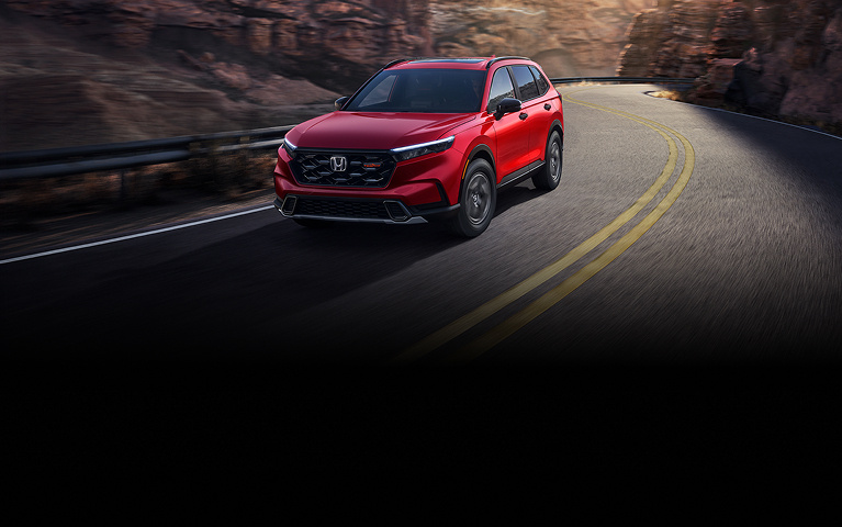 2026 Honda CR-V TrailSport Hybrid in Radiant Red Metallic front view driving on a canyon road (Compact Crossover SUV).