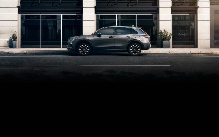 2026 Honda HR-V EX-L in Modern Steel Metallic profile parked on a street against a modern storefront (Subcompact Crossover SUV).