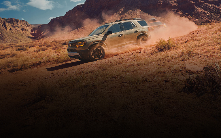 2026 Honda Passport TrailSport Elite in Ash Green Metallic side angle driving trough the dusty desert (Mid-Size SUV).