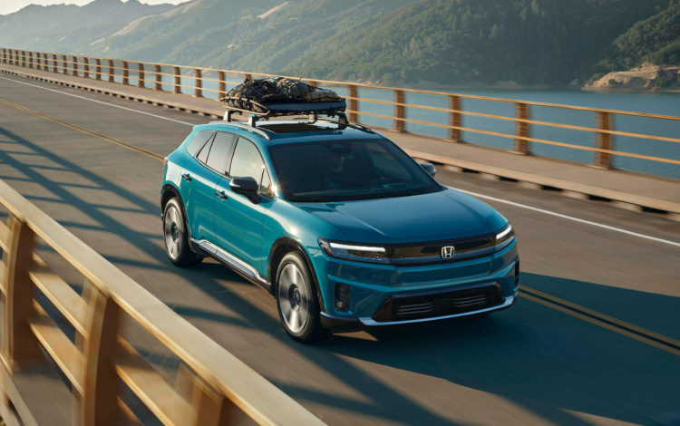 2026 Honda Prologue Elite in North Shore Pearl crossing a bridge in afternoon light, featuring Honda Genuine Accessories.