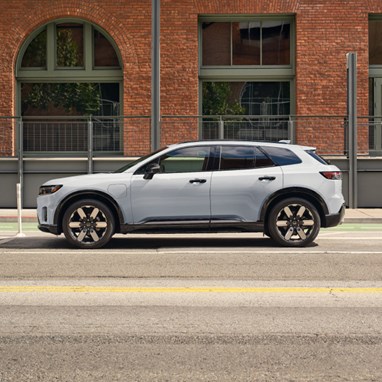 2026 Honda Prologue Elite in Frostline White Pearl, parked on a city road in front of a brick building.