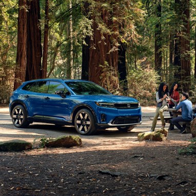 2026 Honda Prologue Elite in Pacific Blue Metallic, parked in a redwood forest, with people enjoying a picnic lunch.