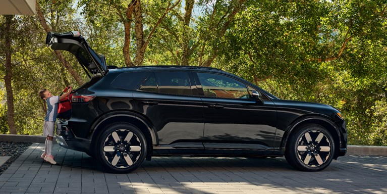2026 Honda Prologue Elite in Raven Black, parked at home with the hatch open, as a kid approaches the rear of the vehicle to load soccer gear for a game.