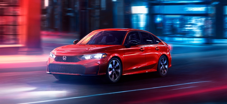 2026 Honda Civic Sedan Sport Touring Hybrid in Rallye Red front three-quarter view driving through a city (Compact Sedan)