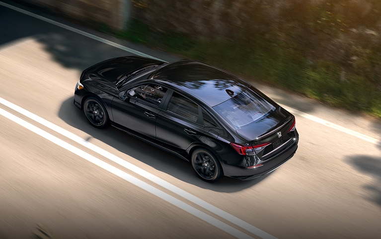 2026 Honda Civic Sedan Sport in Crystal Black Pearl high-angle rear three-quarter view driving on a road (Compact Sedan)