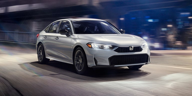 2026 Honda Civic Sedan Sport Hybrid in Solar Silver Metallic front three-quarter view driving on a street (Compact Sedan)