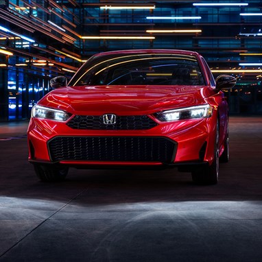 2026 Honda Civic Sedan Sport Touring Hybrid in Rallye Red front view with headlights on (Compact Sedan)